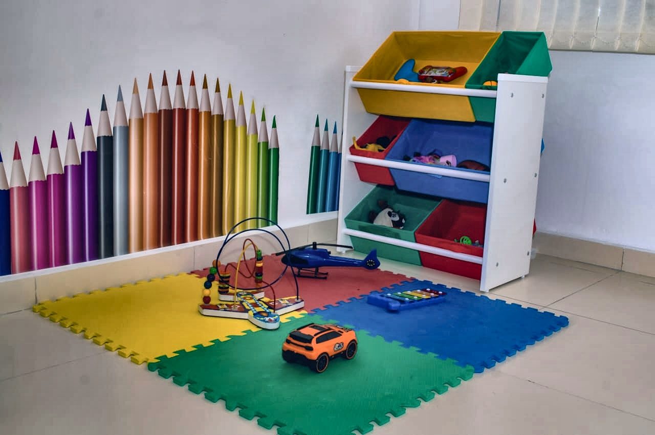 Parede da sala infantil do Núcleo Ser Plural, decorada com lápis de cor em tamanho grande